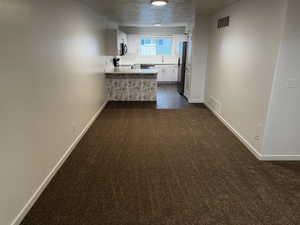 Kitchen featuring white cabinetry, dark colored carpet, a peninsula, light countertops, and stove