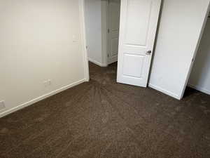 Unfurnished bedroom featuring dark colored carpet and baseboards