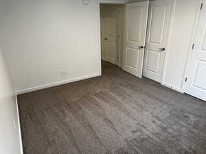 Unfurnished bedroom featuring dark carpet and a closet