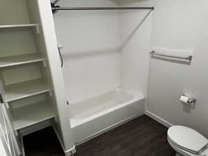 Bathroom featuring dark wood-style flooring and shower / tub combination