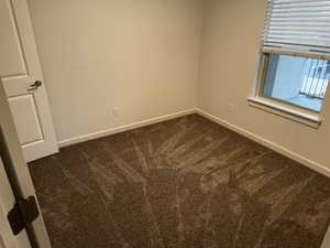 Unfurnished room with dark colored carpet and baseboards