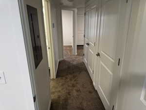 Hall with dark colored carpet and electric panel