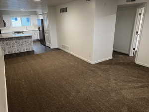 Kitchen with light countertops, white cabinetry, dark carpet, fridge with ice dispenser, and a peninsula