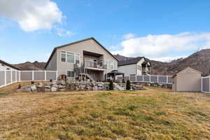 Rear view of property with a balcony, stucco siding, a fenced backyard, a shed, and a patio area