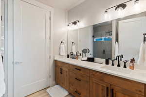Full bath with double vanity, a stall shower, and light wood-type flooring