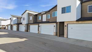 Back of property with stone siding, a residential view, an attached garage, and stucco siding