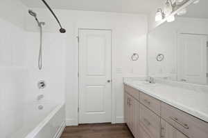 Bathroom featuring vanity, tub / shower combination, and dark wood finished floors