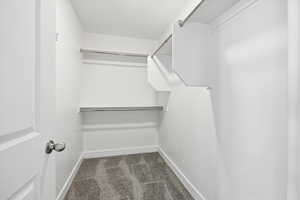 Walk in closet with dark colored carpet
