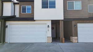 View of front of house featuring an attached garage, concrete driveway, and stucco siding