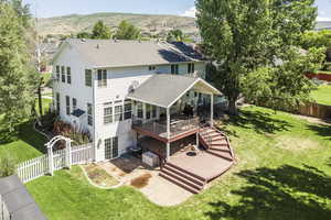 Rear view of property featuring a patio, roof with shingles, a fenced backyard, and a deck with mountain view