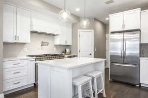 Kitchen with freestanding refrigerator, white cabinets, and a kitchen breakfast bar