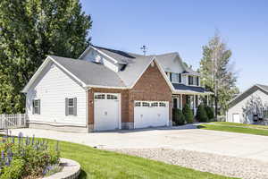 View of front of home with concrete driveway, a garage, a porch, brick siding, and a shingled roof