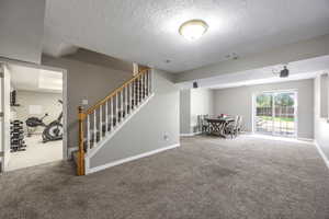 Carpeted living room featuring baseboards and a textured ceiling