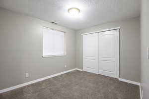 Unfurnished bedroom with carpet, a closet, and a textured ceiling