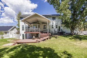 Rear view of house with a wooden deck, a fenced backyard, a ceiling fan, and a gate