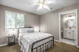 Carpeted bedroom featuring ceiling fan and ensuite bath