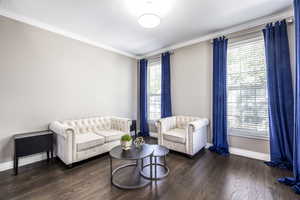 Living room with dark wood-style flooring and ornamental molding