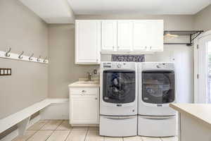 Laundry room featuring independent washer and dryer, light tile patterned floors, cabinet space, and electric panel