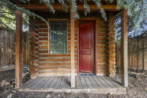 Doorway to property with log siding and a porch