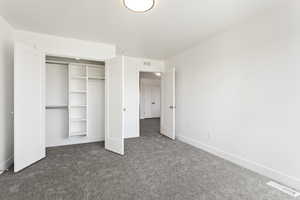 Unfurnished bedroom featuring dark carpet and a closet