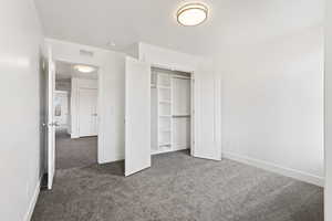 Unfurnished bedroom with dark carpet and a closet
