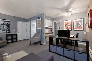 Living room with carpet flooring, a baseboard radiator, and a ceiling fan