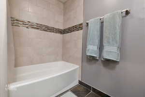 Bathroom featuring shower / bathtub combination with curtain and dark tile patterned flooring