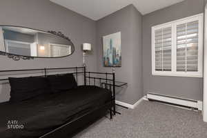 Carpeted bedroom with baseboard heating and baseboards