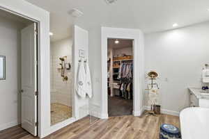 Bathroom with a spacious closet, walk in shower, light wood-style flooring, vanity, and recessed lighting