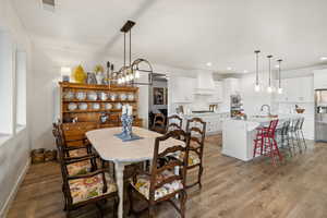 Dining area featuring light wood finished floors and suspended lighting