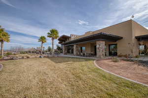 Rear view of property with a lawn, stucco siding, a patio area, and stone siding