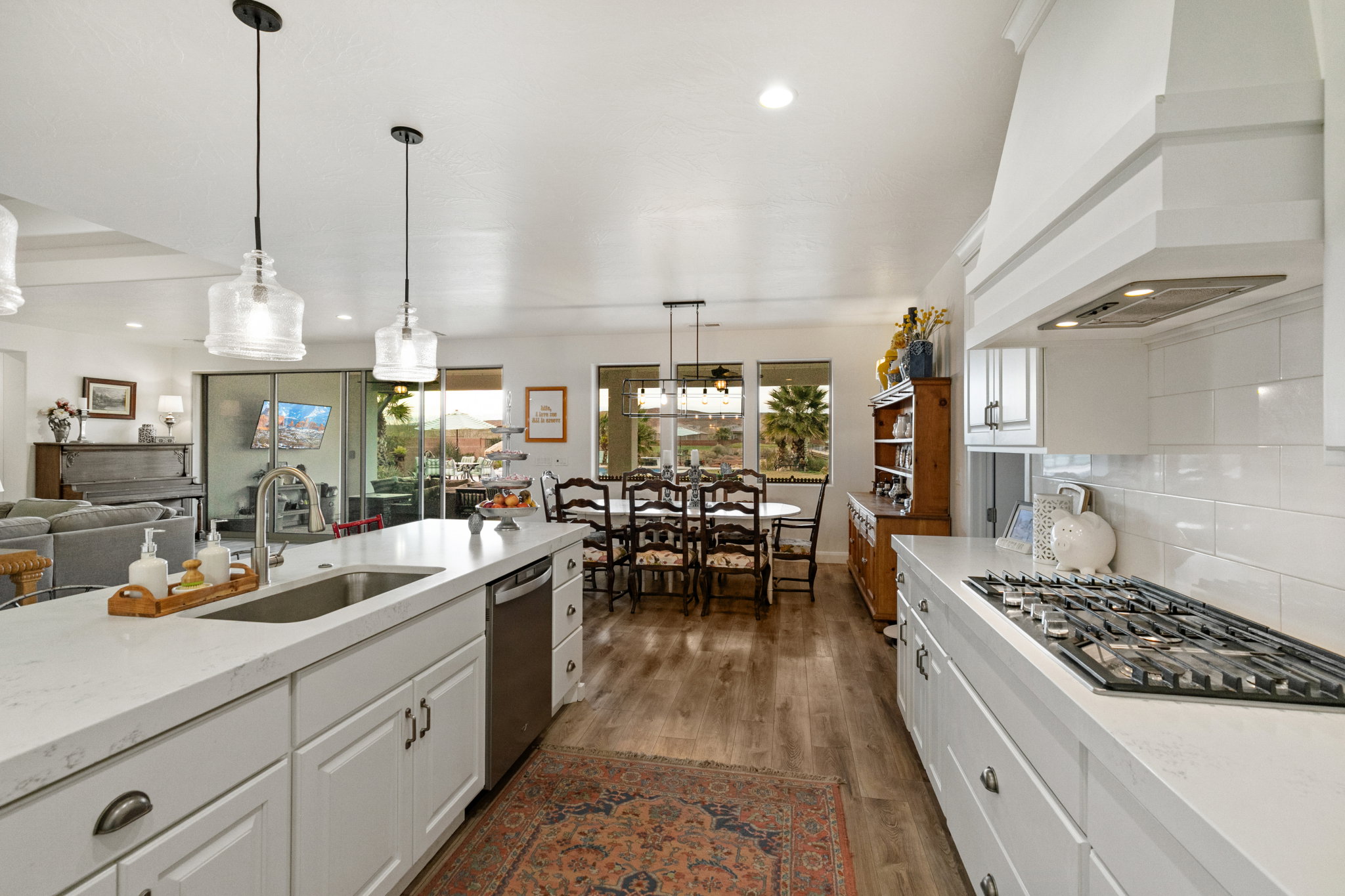 Kitchen with white cabinetry, decorative light fixtures, light stone countertops, and open floor plan