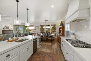 Kitchen with white cabinetry, decorative light fixtures, light stone countertops, and open floor plan