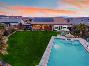 Back of house featuring an outdoor living / dining area, a patio, solar panels, a tiled roof, and a fenced backyard