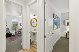 Hall with light colored carpet and light wood-style flooring