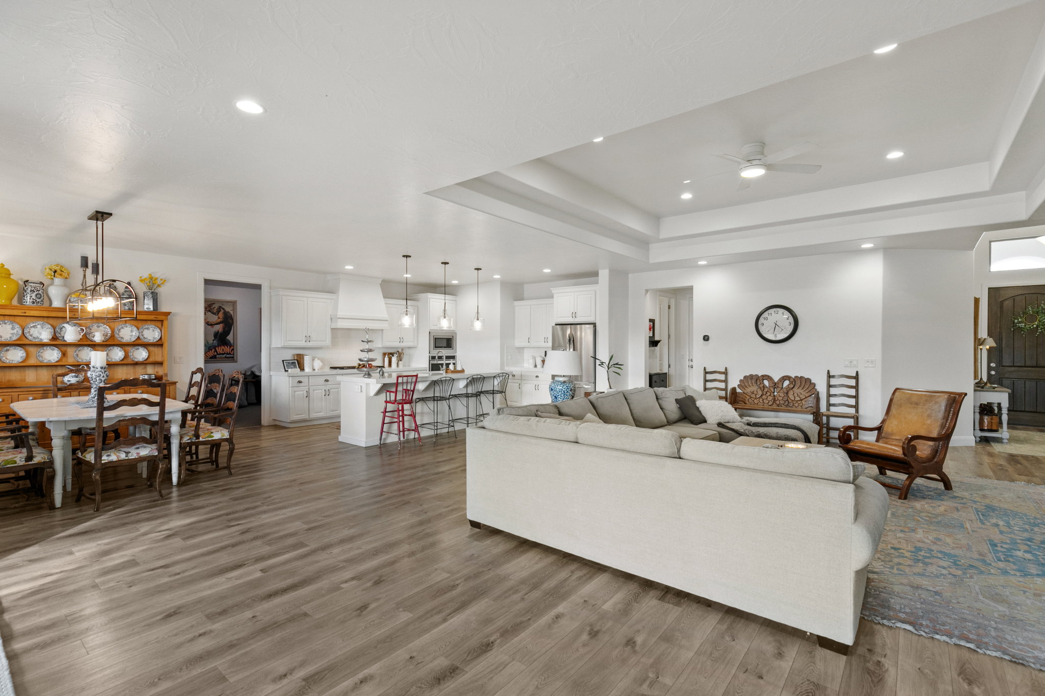 Living room with a ceiling fan, light wood-style flooring, recessed lighting, and a raised ceiling