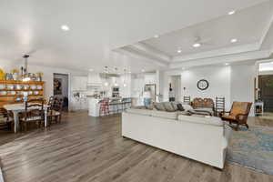 Living room with a ceiling fan, light wood-style flooring, recessed lighting, and a raised ceiling