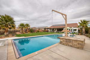 View of swimming pool with patio surround and a fenced backyard