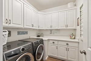 Laundry room with separate washer and dryer, wood finished floors, and cabinet space