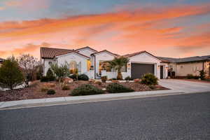Mediterranean / spanish house with driveway, stucco siding, a tile roof, and an attached garage