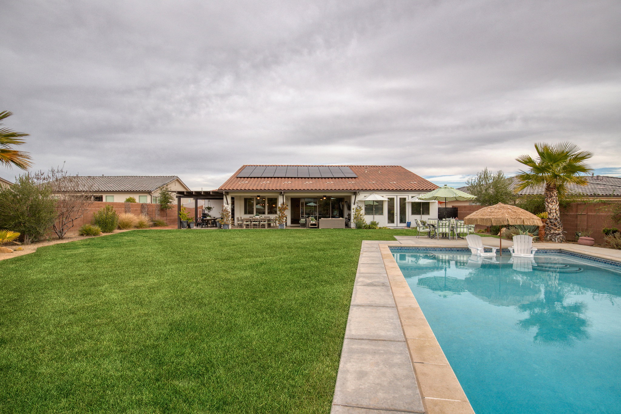 Rear view of house with outdoor dining space, roof mounted solar panels, a patio area, a tiled roof, and a fenced backyard