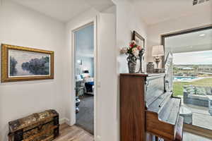 Hallway with light wood-type flooring and light colored carpet