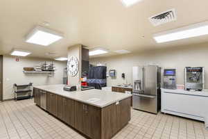 Kitchen featuring dark wood finish cabinets, high quality fridge, light countertops, modern cabinets, and a center island