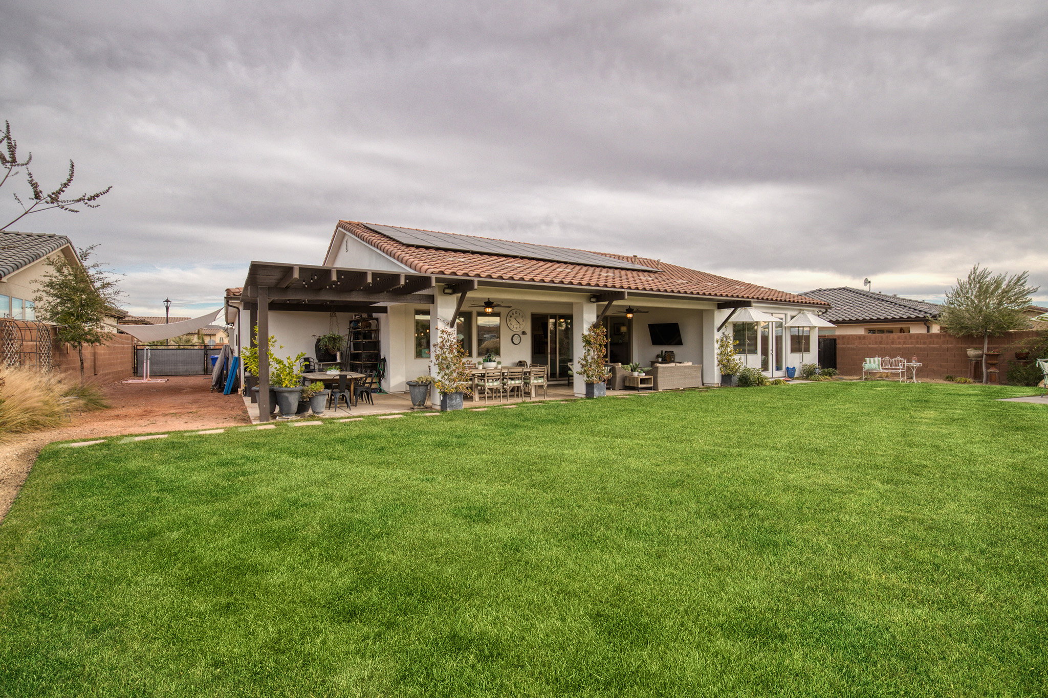 Back of house with solar panels, a ceiling fan, a patio, an outdoor living / dining area, and a fenced backyard