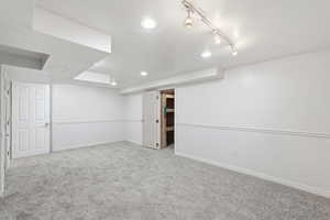 Finished basement featuring carpet and track lighting