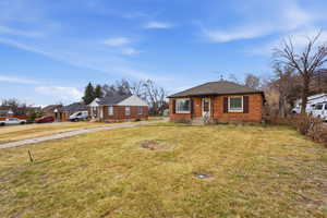 Bungalow-style home with brick siding, a residential view, a front lawn, and a shingled roof