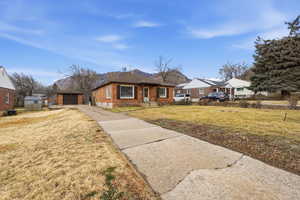View of front of property featuring an outbuilding, concrete driveway, a front yard, brick siding, and a garage