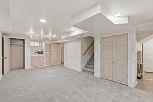 Finished basement featuring stairs and light carpet