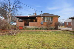 View of front facade with a chimney, a front yard, a patio, and brick siding