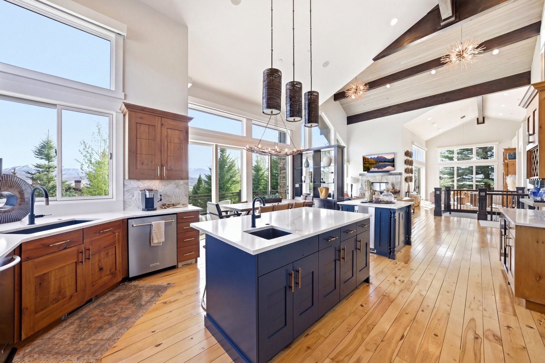 Open-concept kitchen featuring two-tone cabinetry, light wood-finish flooring, two large kitchen islands with sinks, and stainless steel appliances